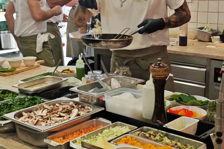 Chefs in a kitchen preparing food with fresh ingredients on counters.