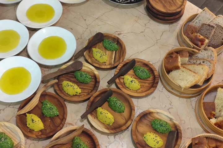 Plates of olive oil, bread slices, and pesto-covered items on a counter.
