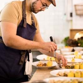 Chef plating dishes with precision in a kitchen setting.
