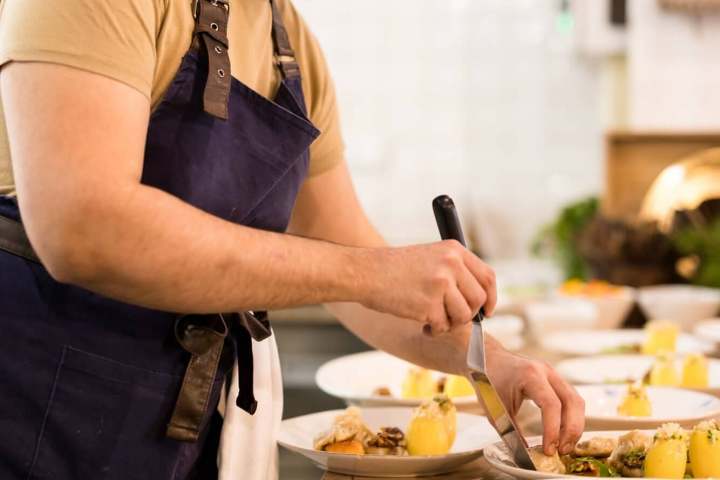 Chef plating dishes with precision in a kitchen setting.