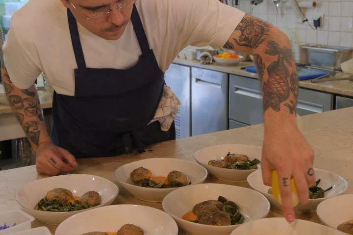 Chef plating dishes with vegetables in a kitchen setting.