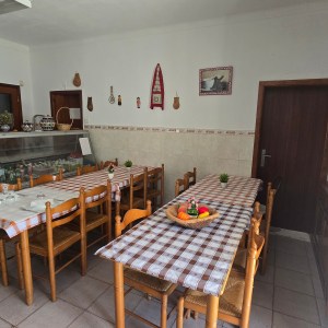 Dining room with two tables, checkered tablecloths, decor on walls, and a display cabinet.