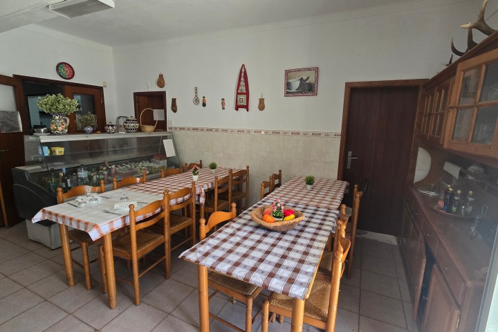Dining room with two tables, checkered tablecloths, decor on walls, and a display cabinet.