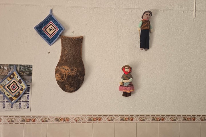 Decorative wall items include dolls, a woven ornament, a calendar, and a wood-hanging on a tiled background.
