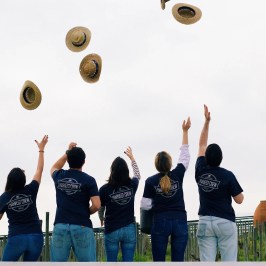 Group of people tossing hats in the air outdoors.