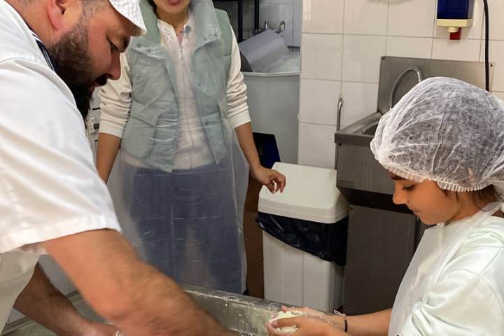 Cheesemaker guiding a family through traditional cheese making in Portugal
