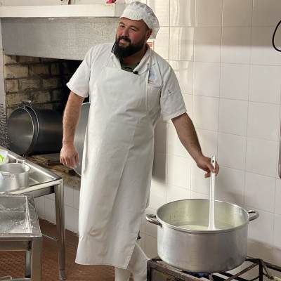 Cheesemaker heating sheep's milk in the dairy before cheese making